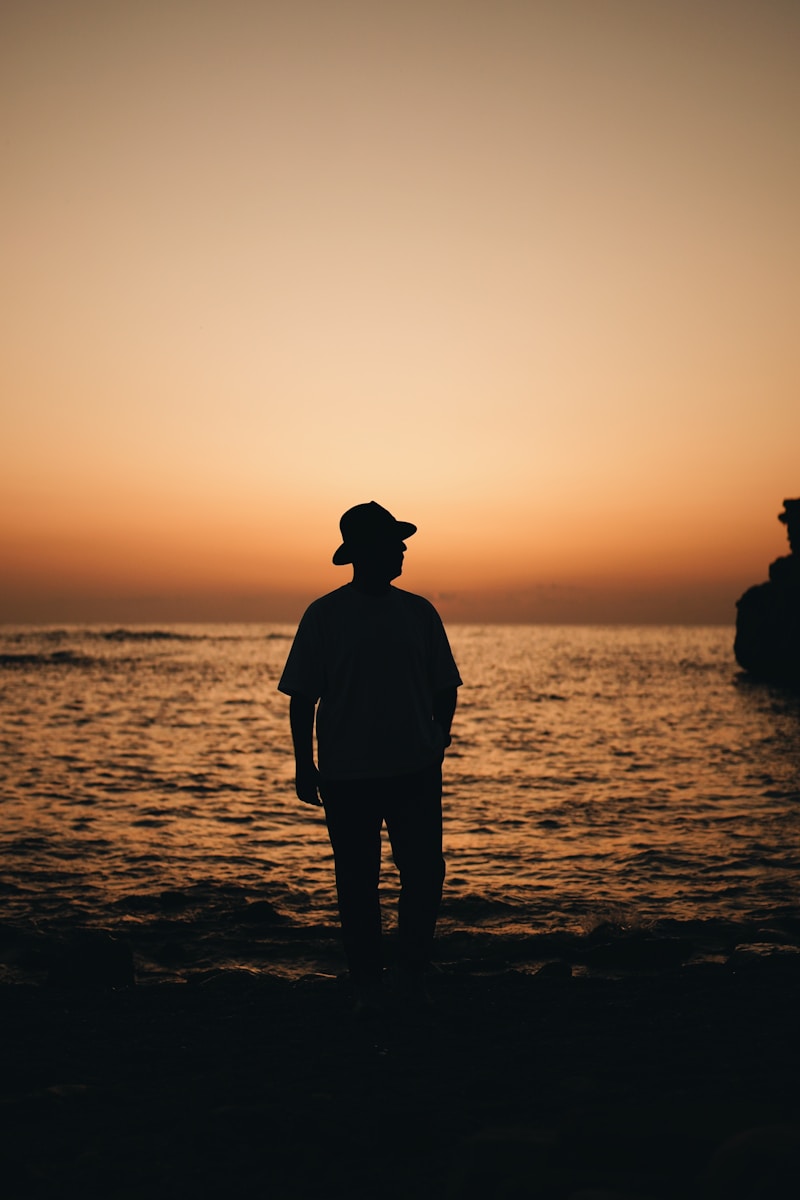 A man standing on a beach at sunset